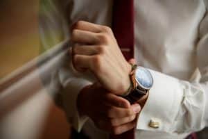 Man with red tie adjusting watch